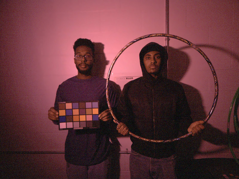 two people holding a ColorChecker under magenta LED